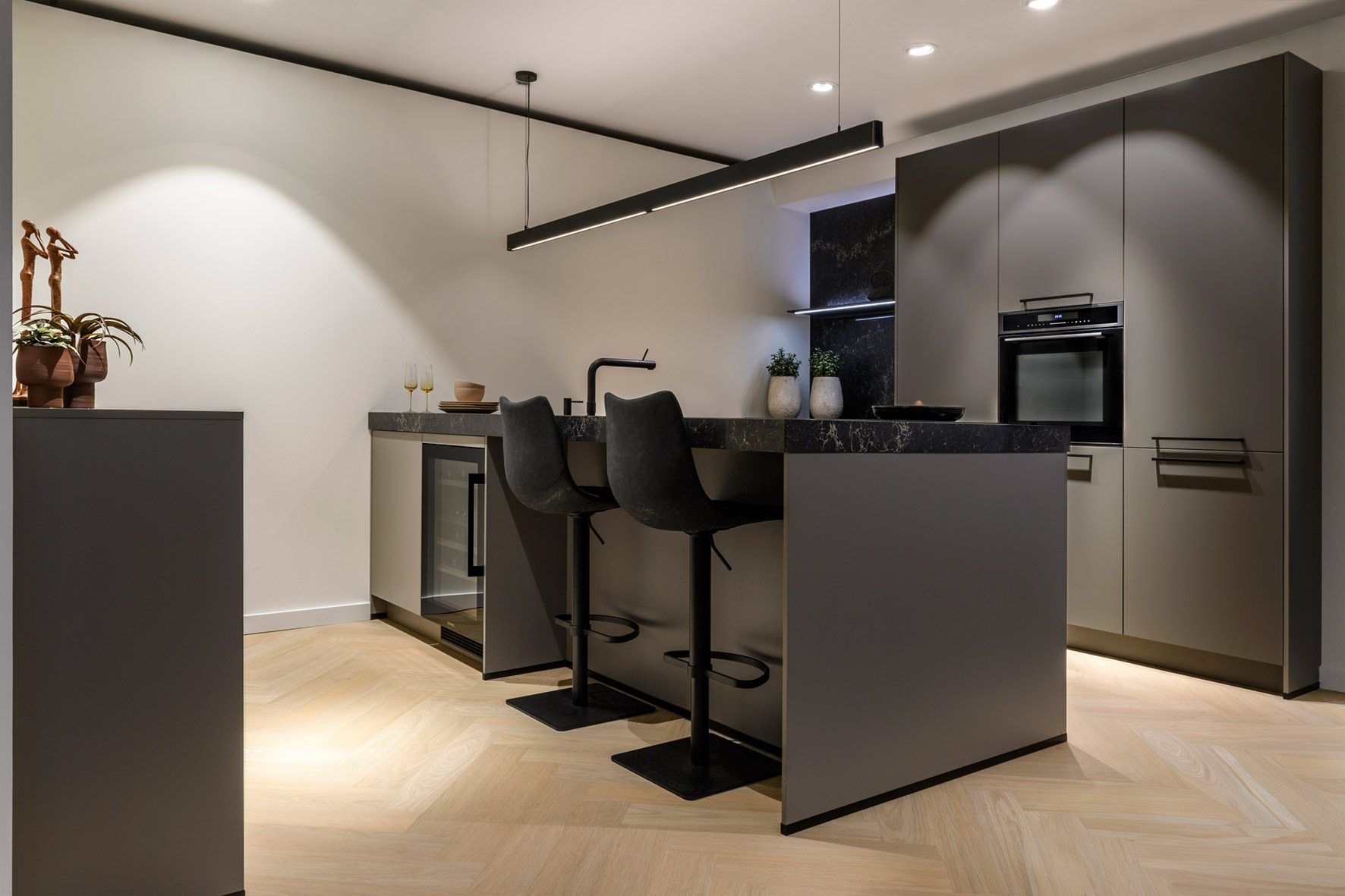 Donkere keuken met kookeiland, bargedeelte en wandmeubel